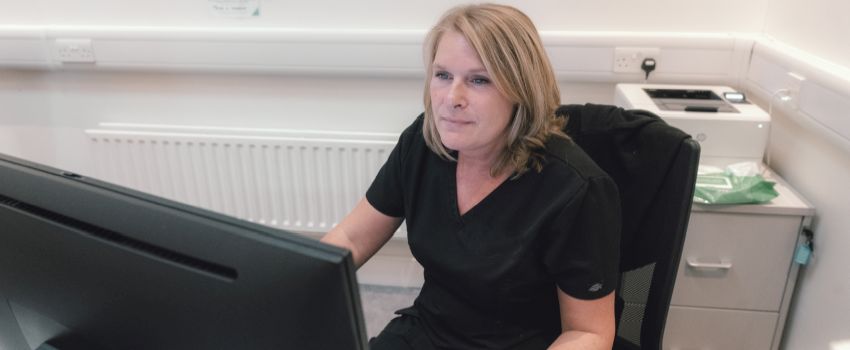 A woman working as a veterinary receptionist is focused on her computer screen.